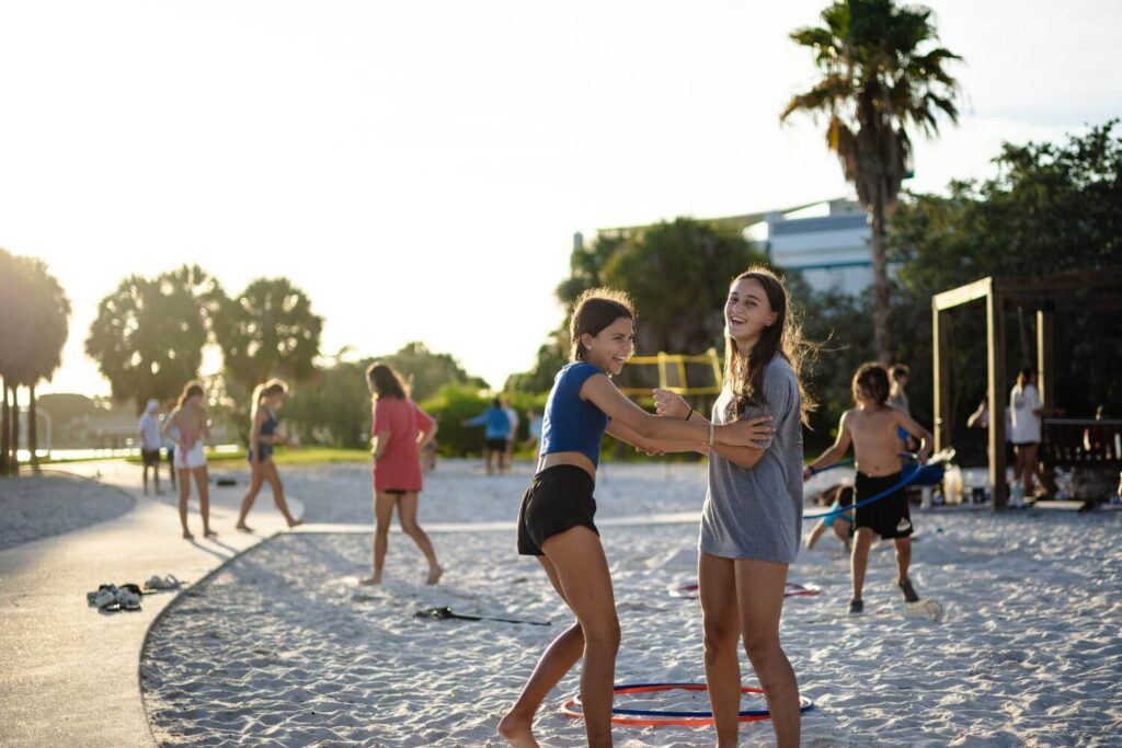 athletes at overnight sports camp enjoying a dance party with hula hoops on the beach in FL