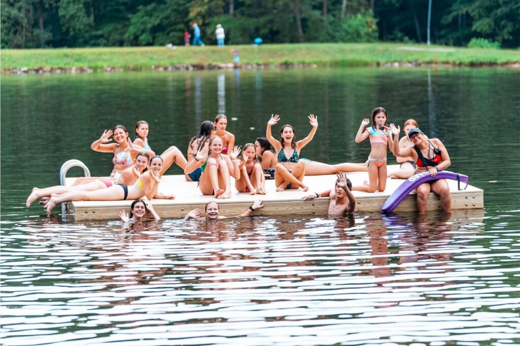 Group of campers at Signature Sports Camp on a floating dock in a lake on campus