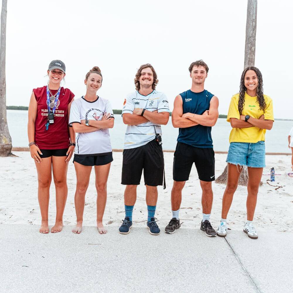 5 Signature Sports Camp coaches standing side by side on the beach in FL