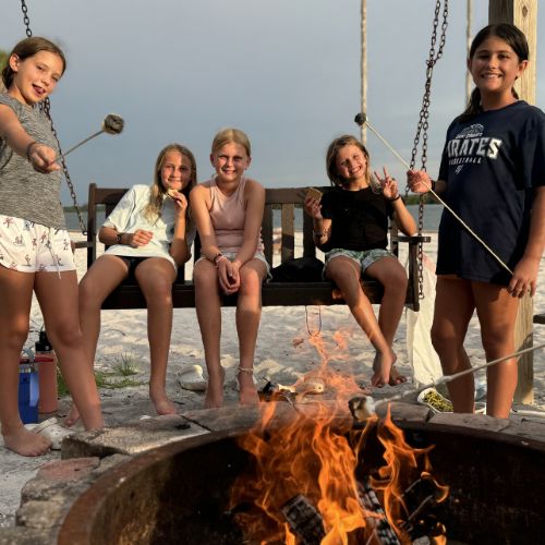 Girls at signature sports camp roasting marshmallows by the bonfire