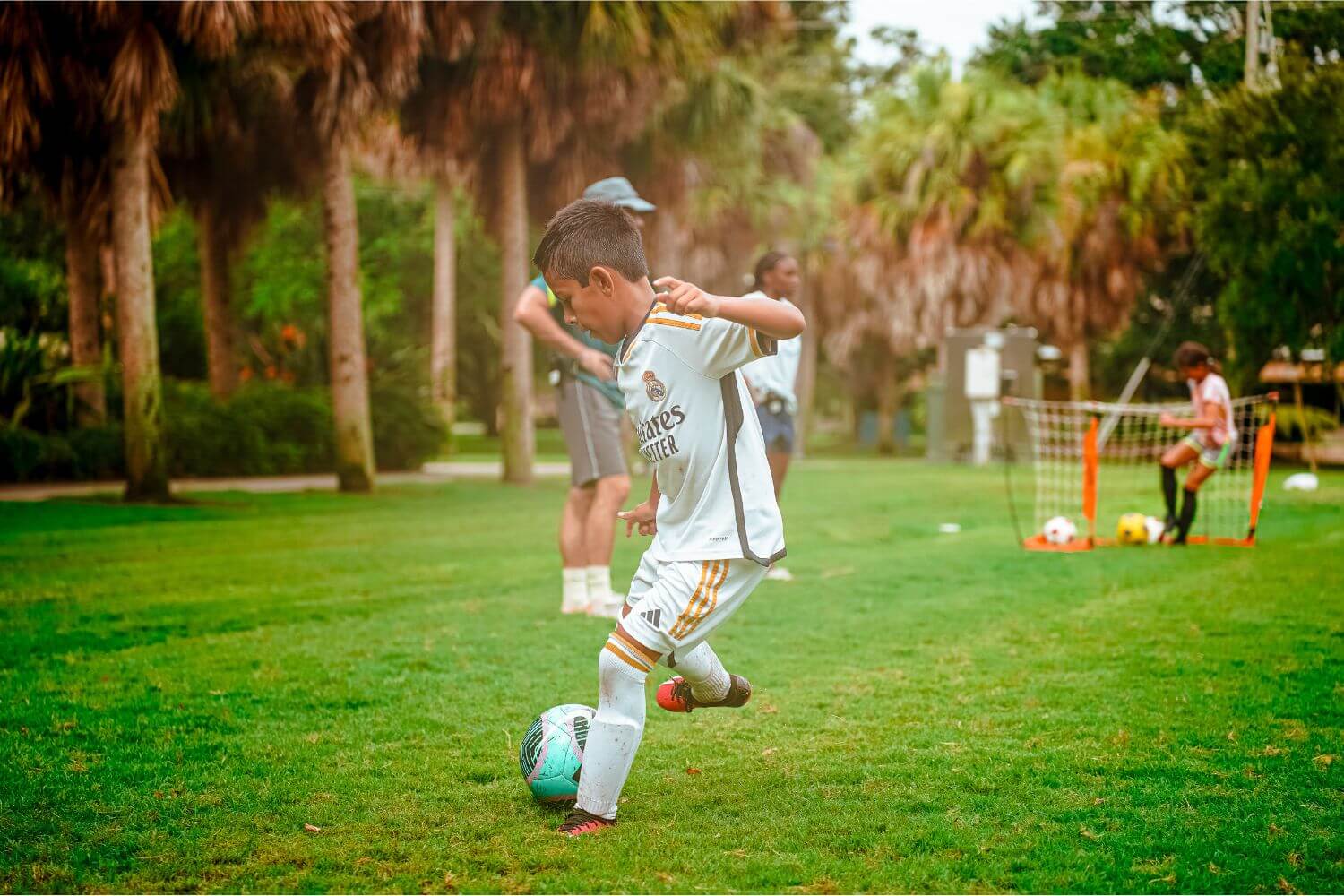 Boy dribbling a teal soccer ball during sports camp