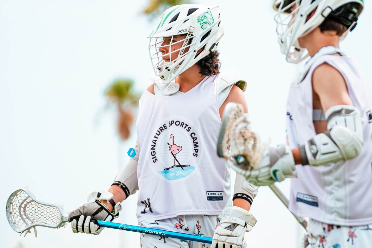 Boys wearing helmets and signature sports camp uniforms holding their lacrosse sticks