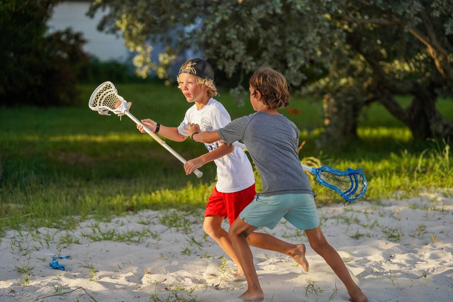 Boys playing lacrosse on the beach during overnight sports camp