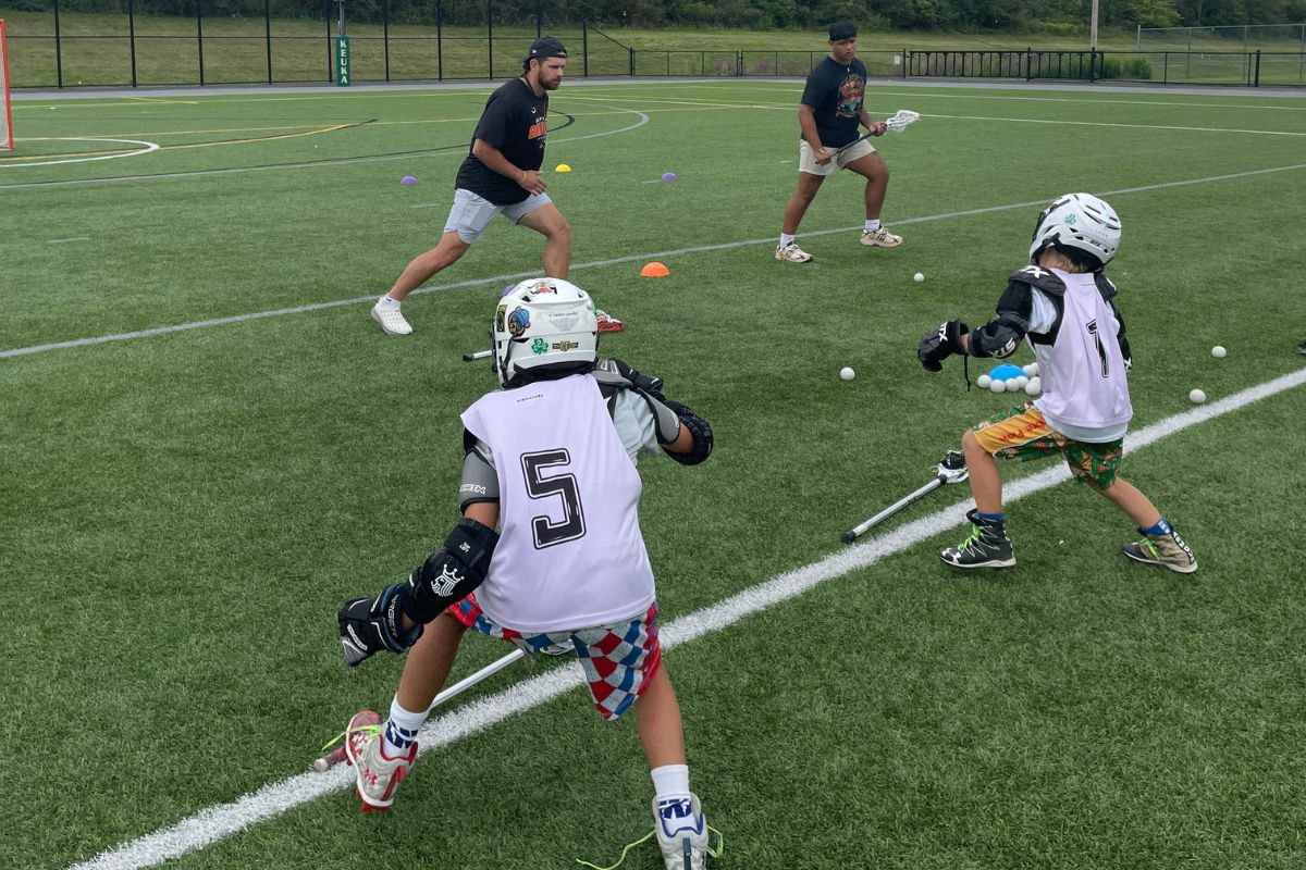 Lacrosse coaches and young lacrosse players during one on one training