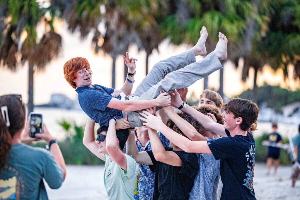 Friend being carried by a group of guys having fun