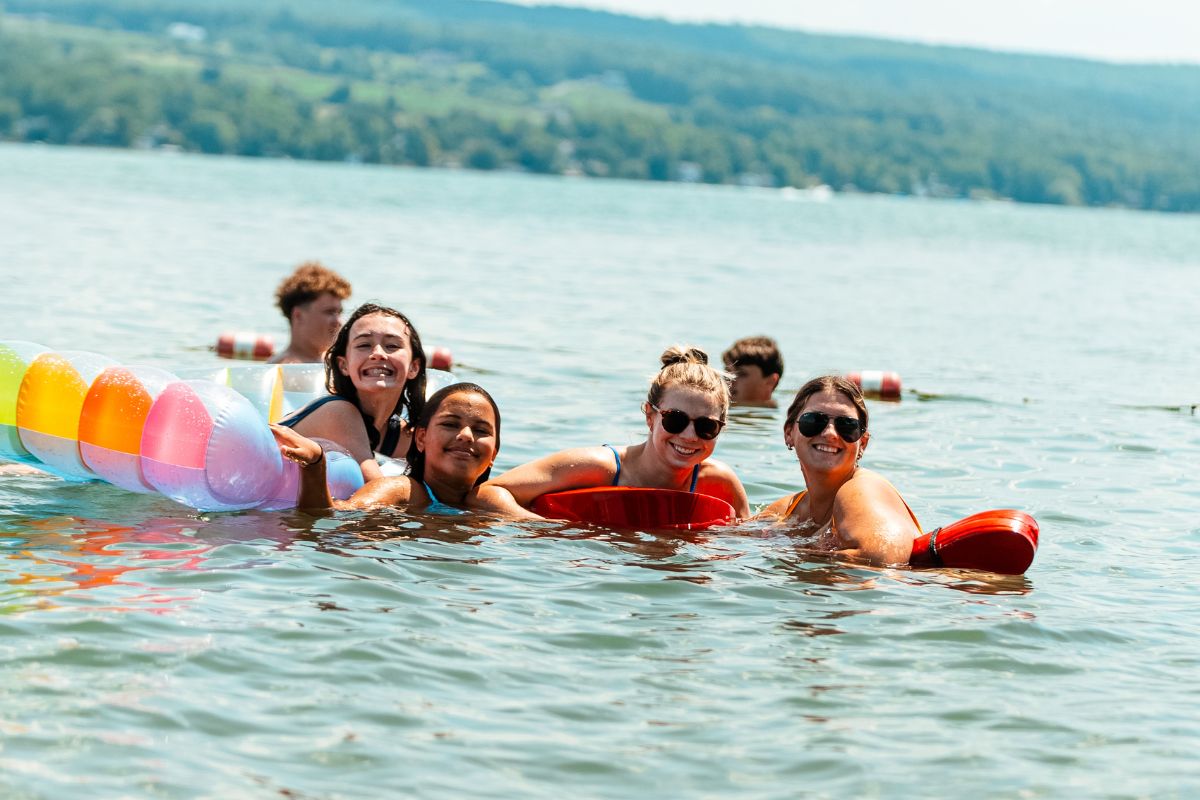 Girls at summer camp swimming in the lake with lifeguards