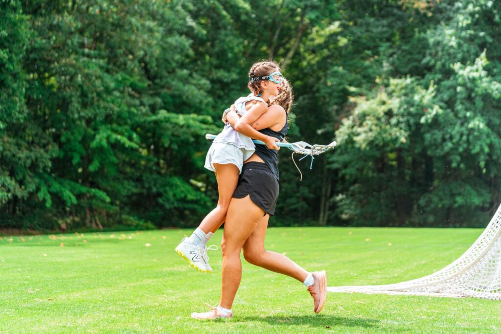 Coach holding up a young lacrosse player in celebration