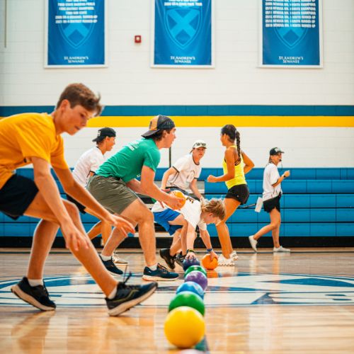 Kids at sports camp playing a game of dodgeball on an indoor court