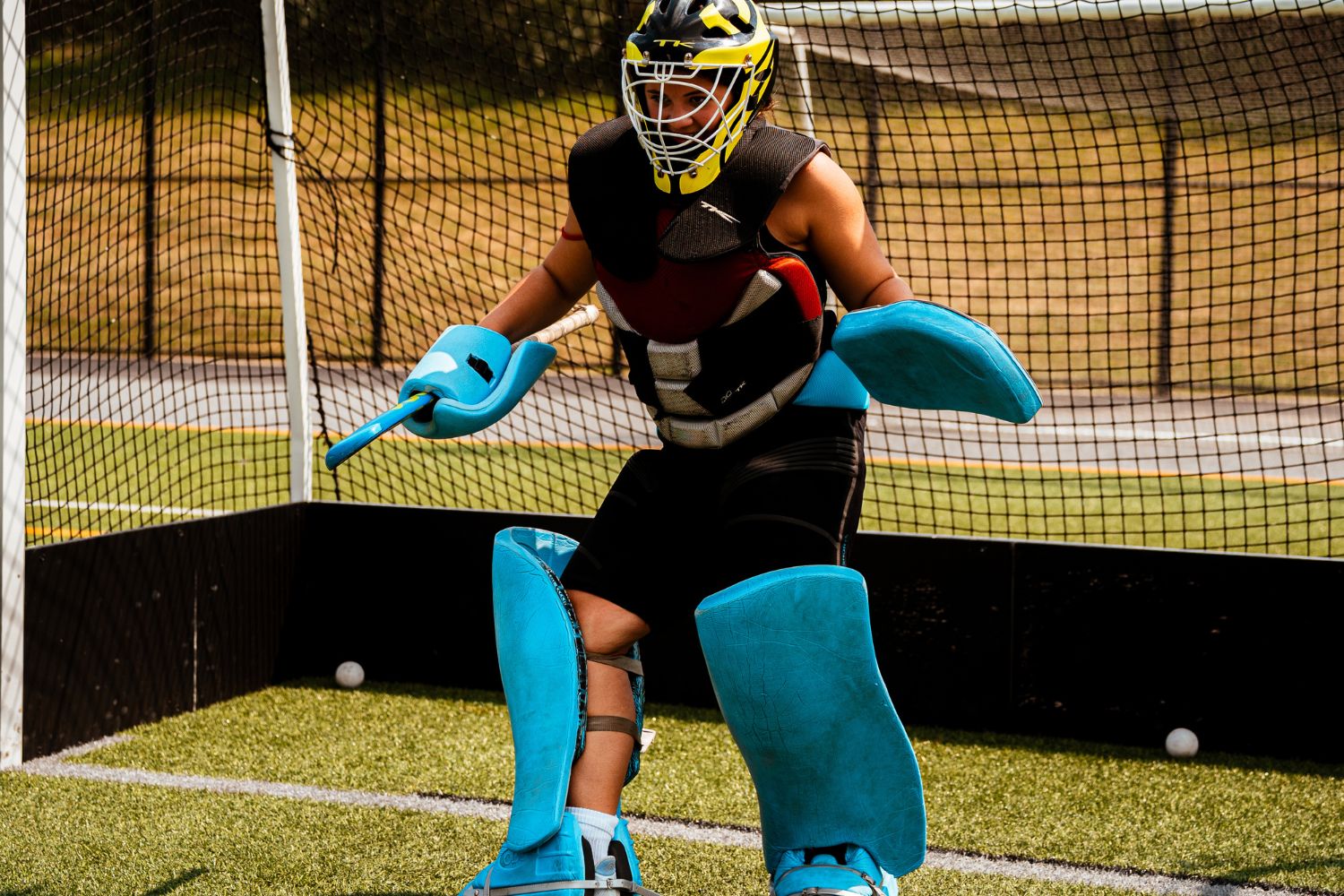 Field hockey goalie wearing pads in front of the goal