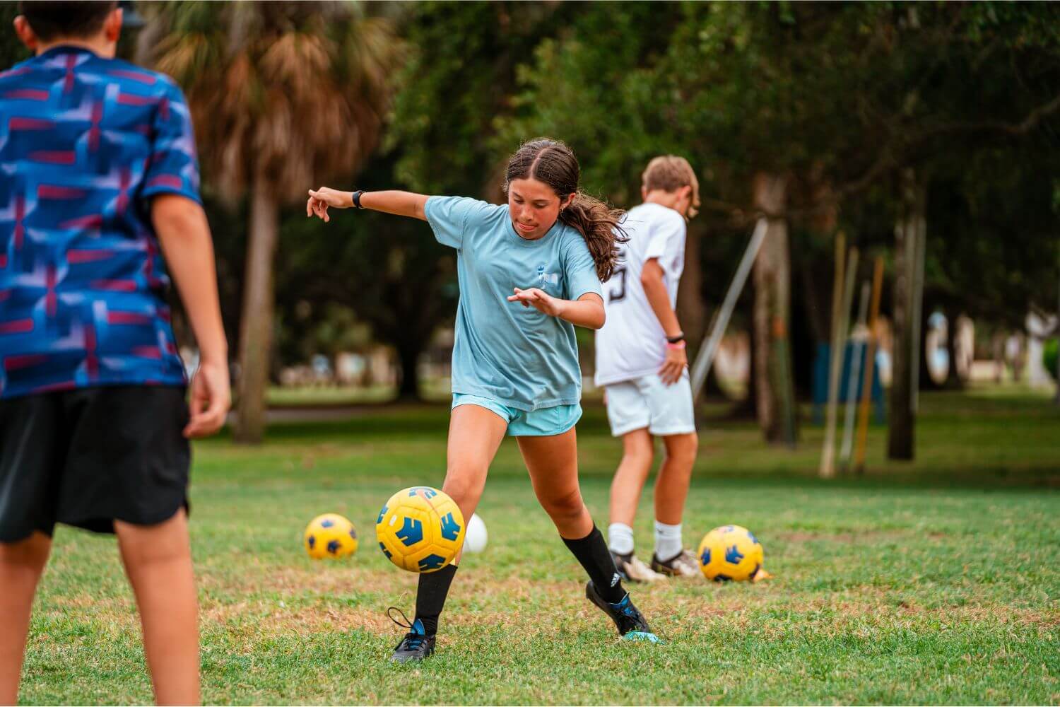 Girl dribbling yellow ball during soccer practice