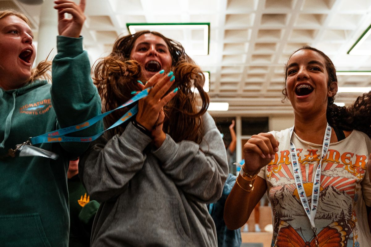 Three girls cheering with excitement for their friends on stage