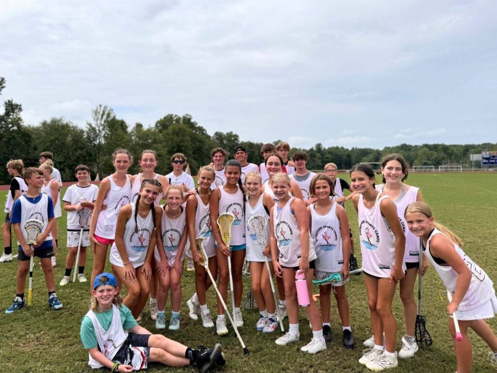 A group of young lacrosse players pose for a photo at sports camp