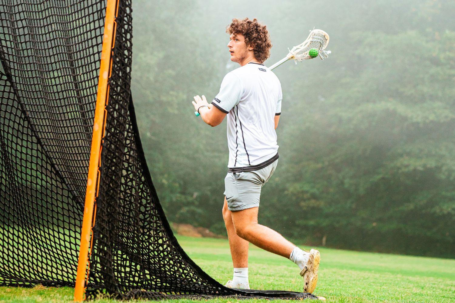 Coach near lacrosse net holding a lacrosse stick