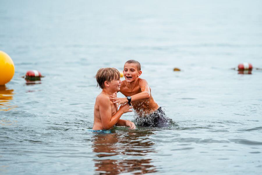 Boys splashing in the lake during sports camp