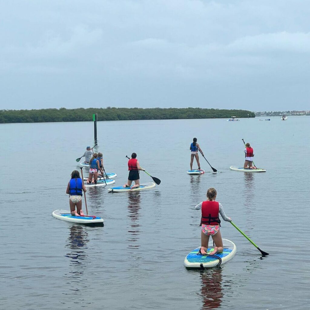 campers at Signature's FL overnight sports camp enjoying paddleboarding on the bay