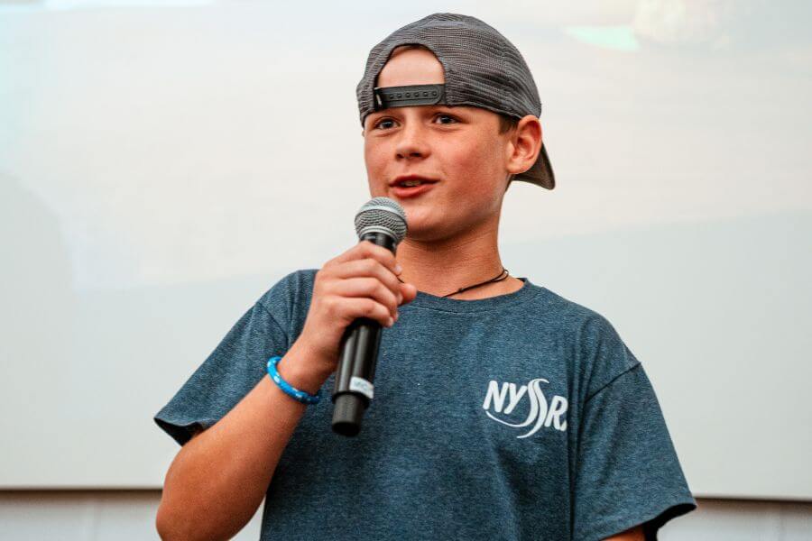 Boy wearing a backwards hat holding a microphone