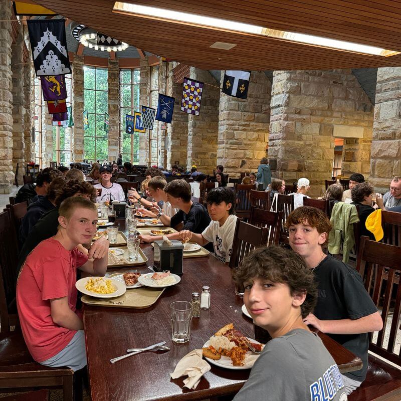 A table of boys smile for a photo in the food hall at signature sports camp