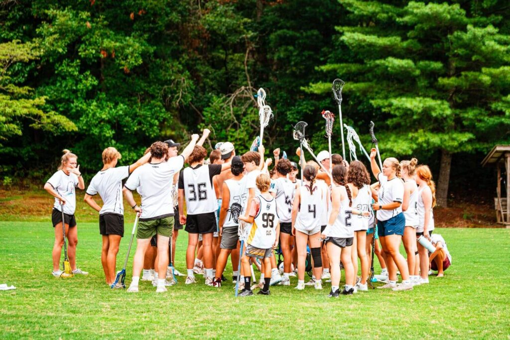 A group of lacrosse players at summer sports camp huddle in together