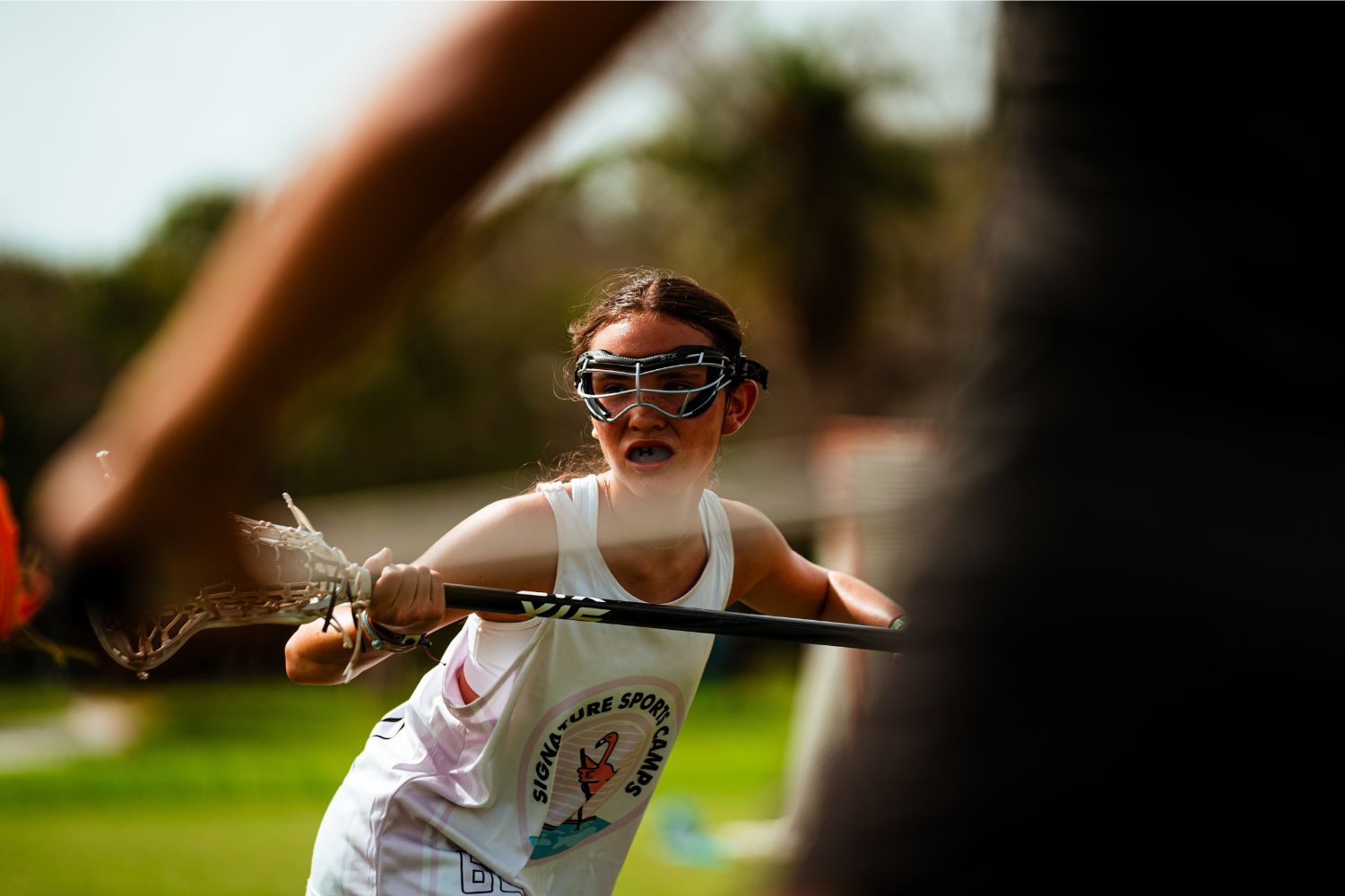 Female lacrosse player holding her stick during practice at overnight sports camp