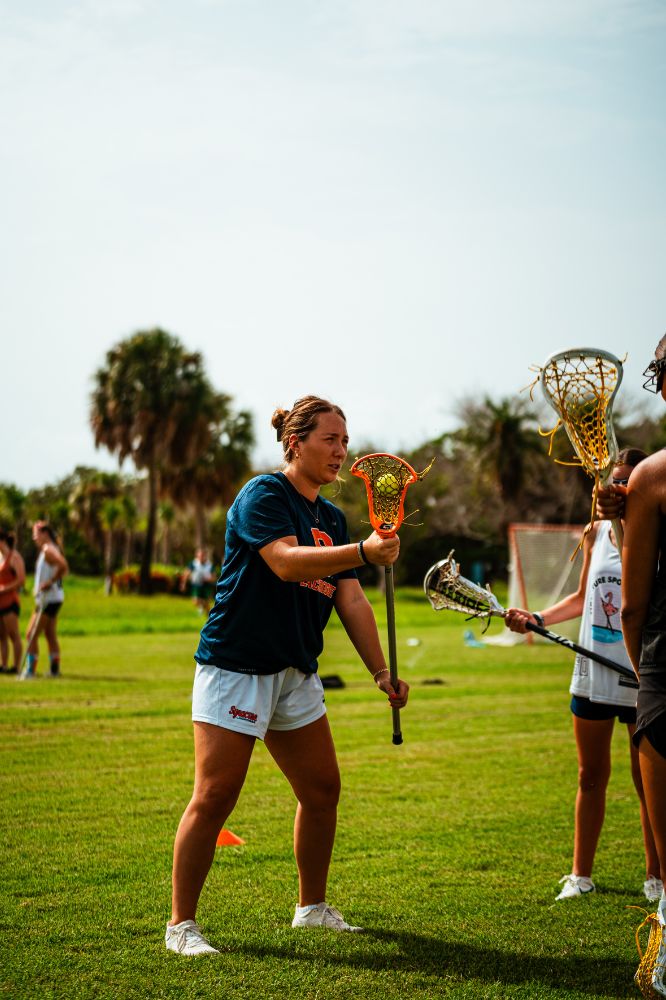 Lacrosse professional player instructing young girls at lacrosse camp