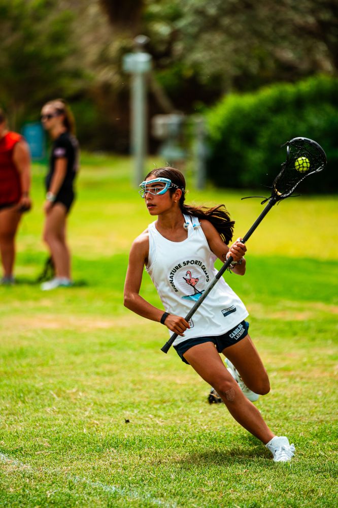 Girl lacrosse player running during drills at lacrosse camp