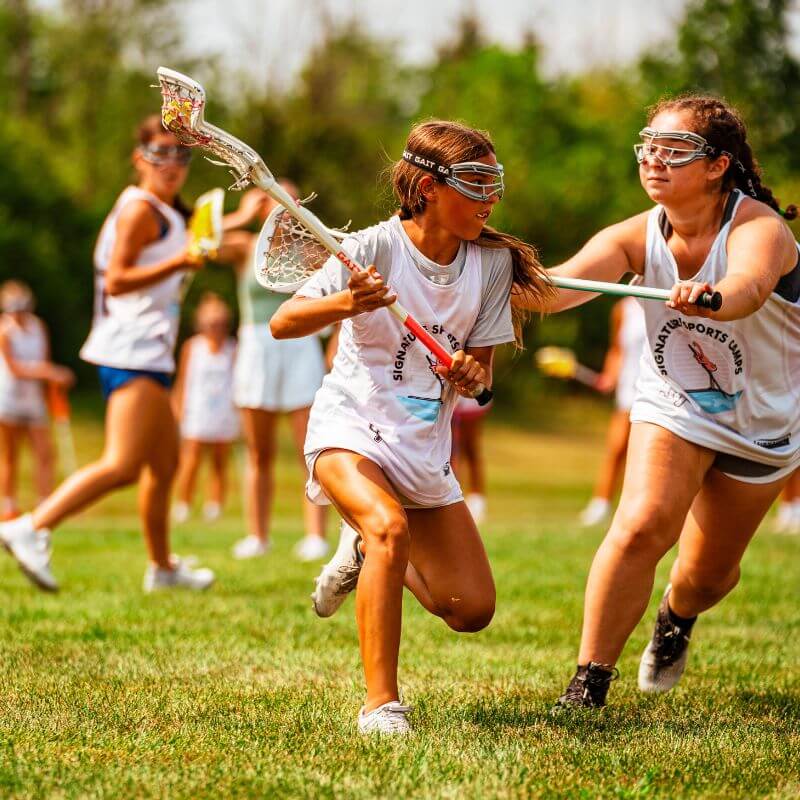 Two girls during a defensive play at lacrosse camp practice