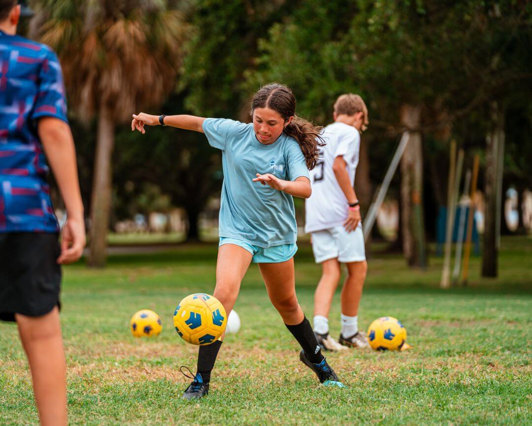 Girl dribbling yellow soccer ball during practice at signature sports camps