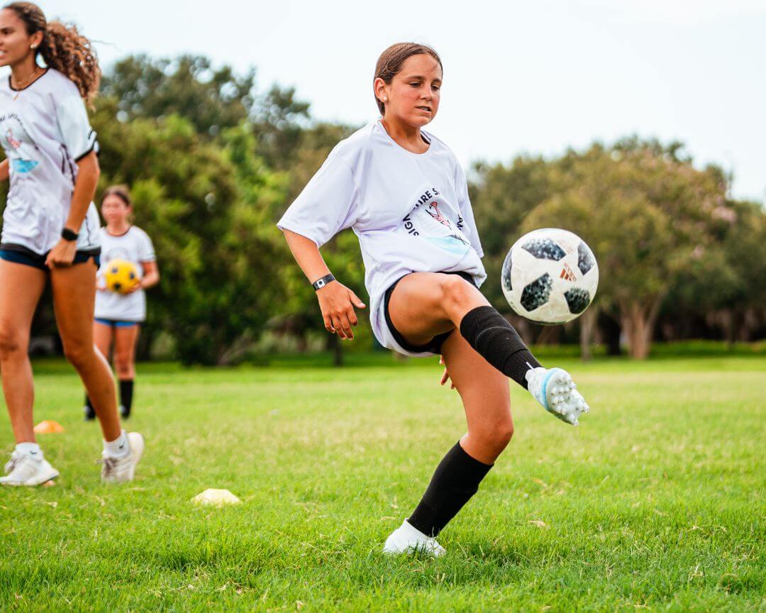 Girl dribbling a white soccer ball during practice at signature sports camps