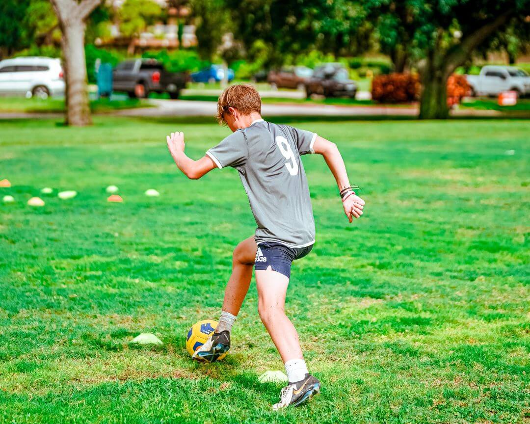Boy wearing a grey number 9 jersey practicing soccer drills at signature sports camp