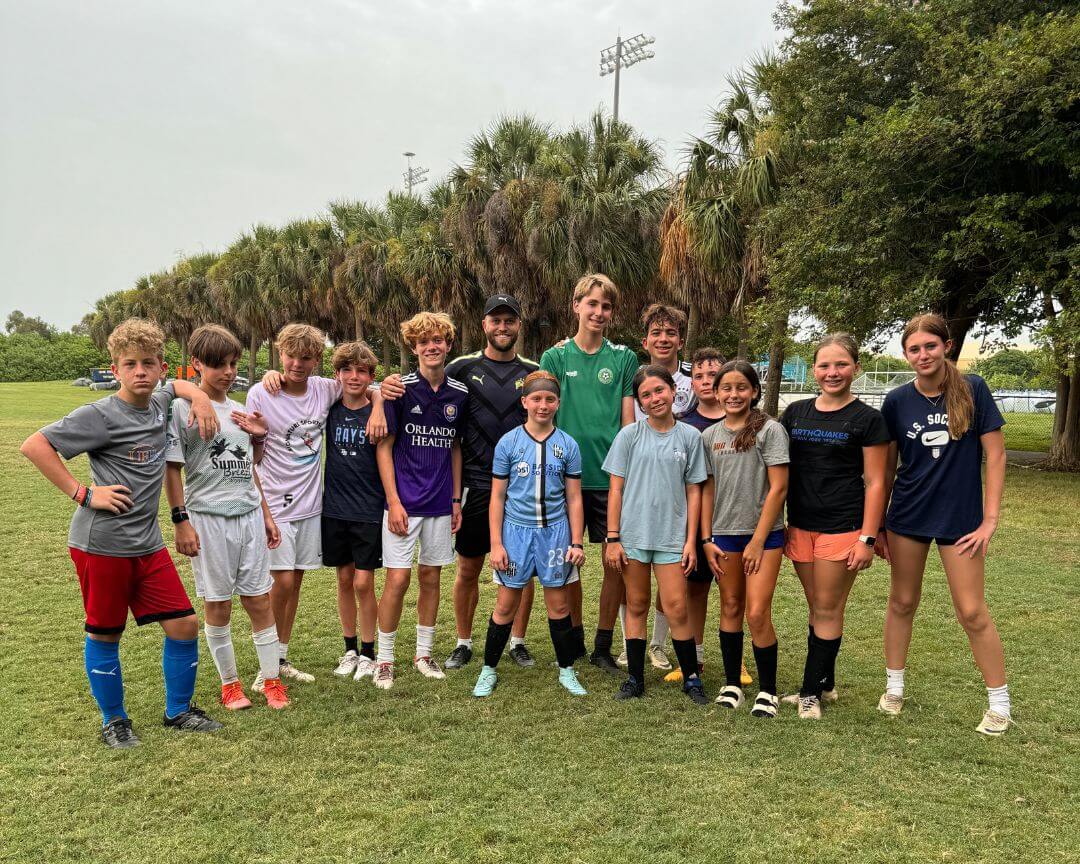 Group of youth athletes at soccer camp pose for a photo with pro soccer player Nicky Law after practice