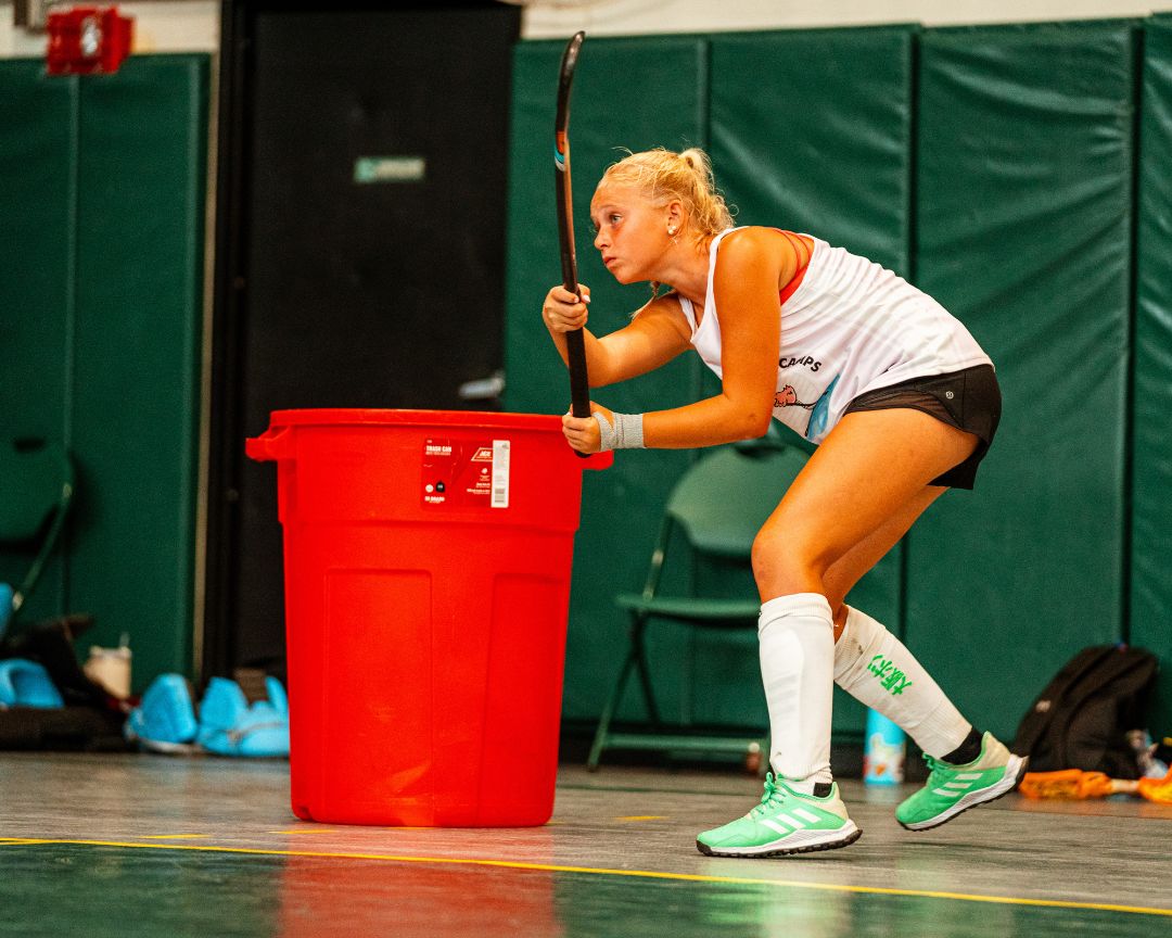 Girl practicing field hockey indoors at signature sports camp