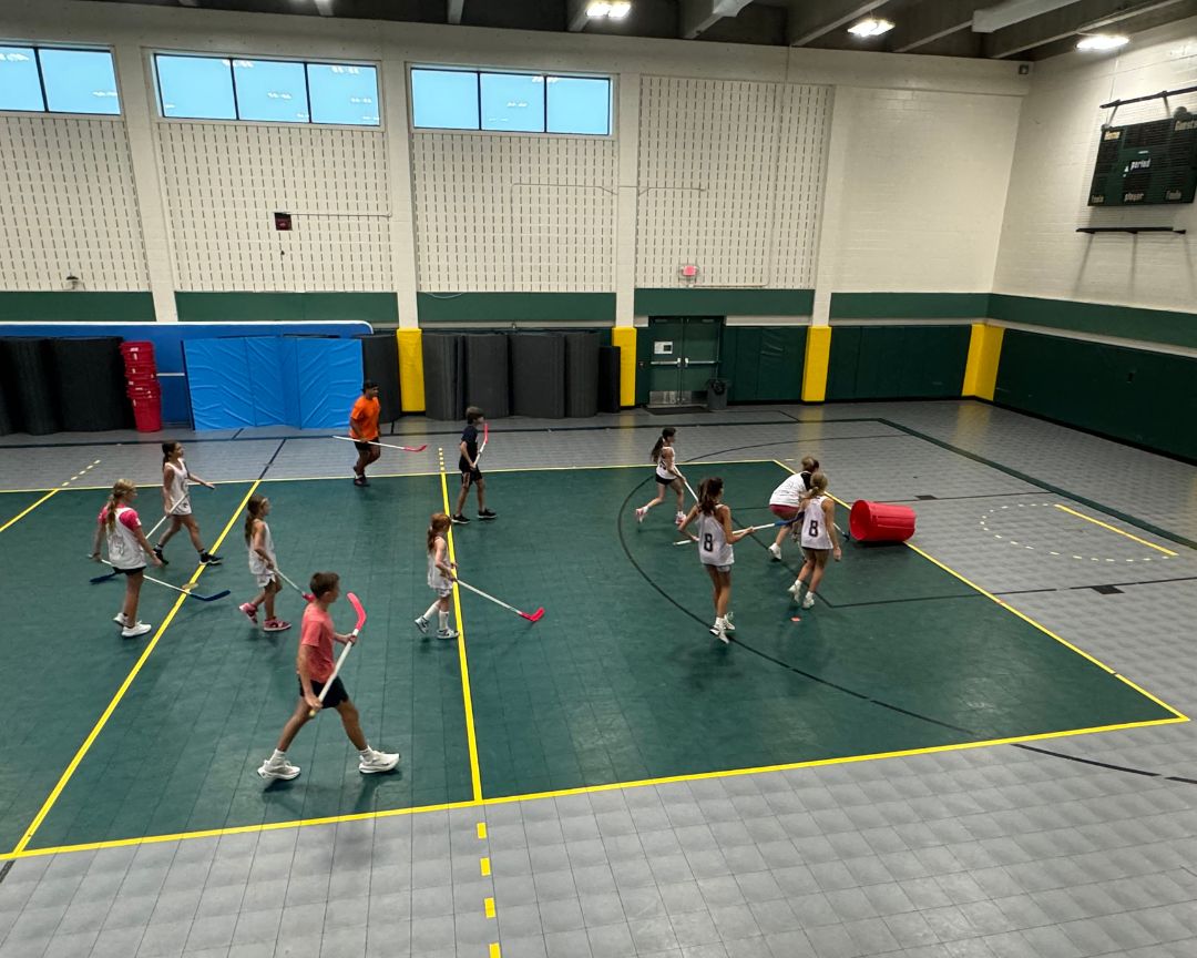 +Kids at signature sports camp competing in a field hockey scrimmage indoors