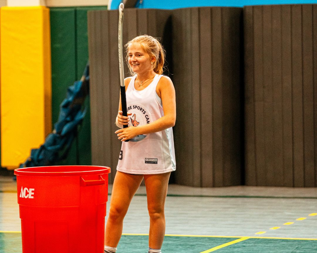 Young signature sports camp attendee smiles during field hockey practice