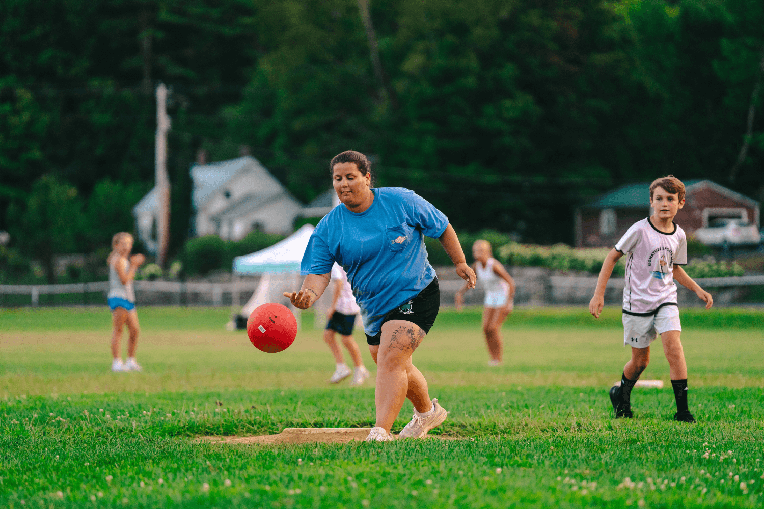 Coach pitching a kickball during an afternoon game