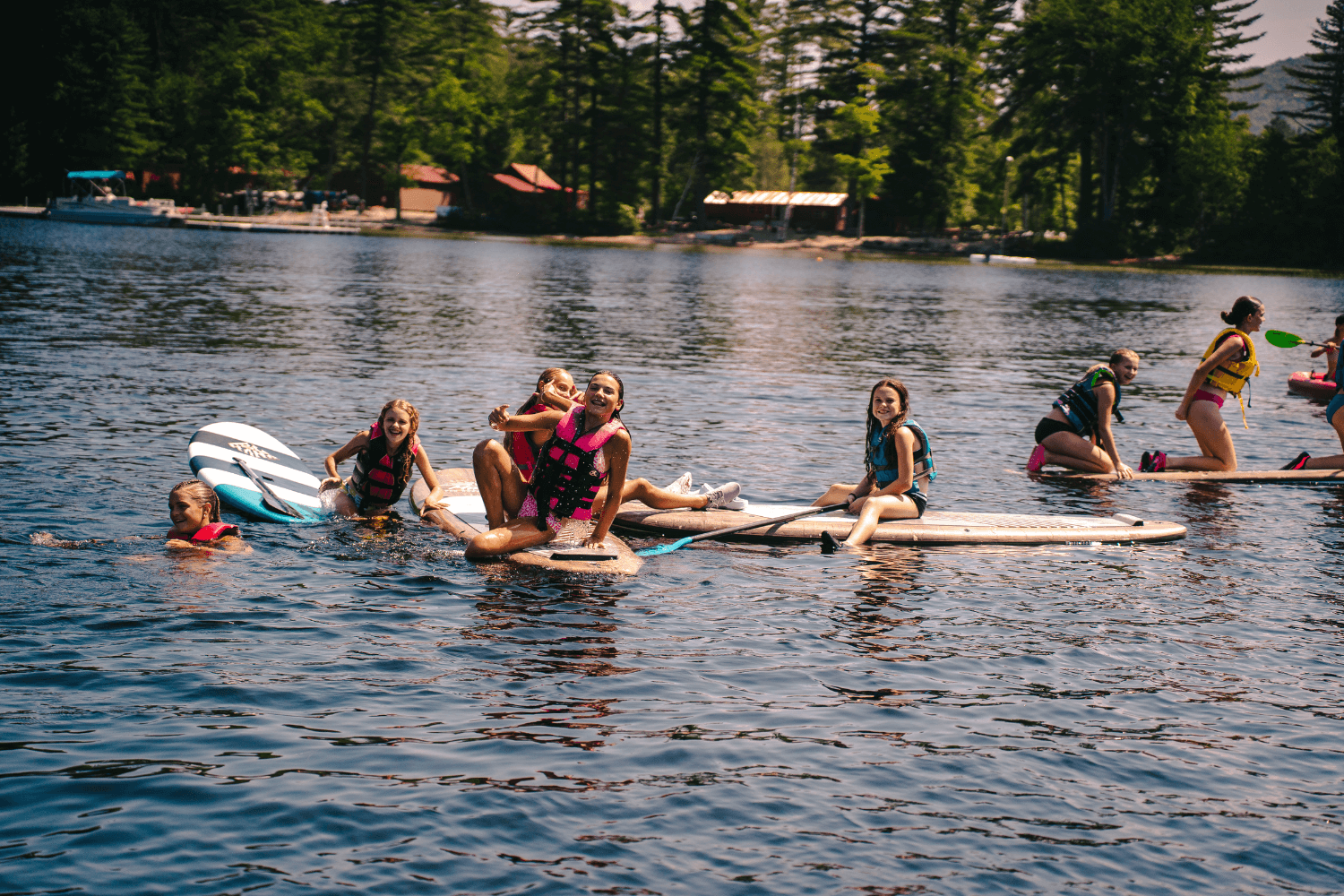 Girls stand up paddleboarding on the lake at sports camp