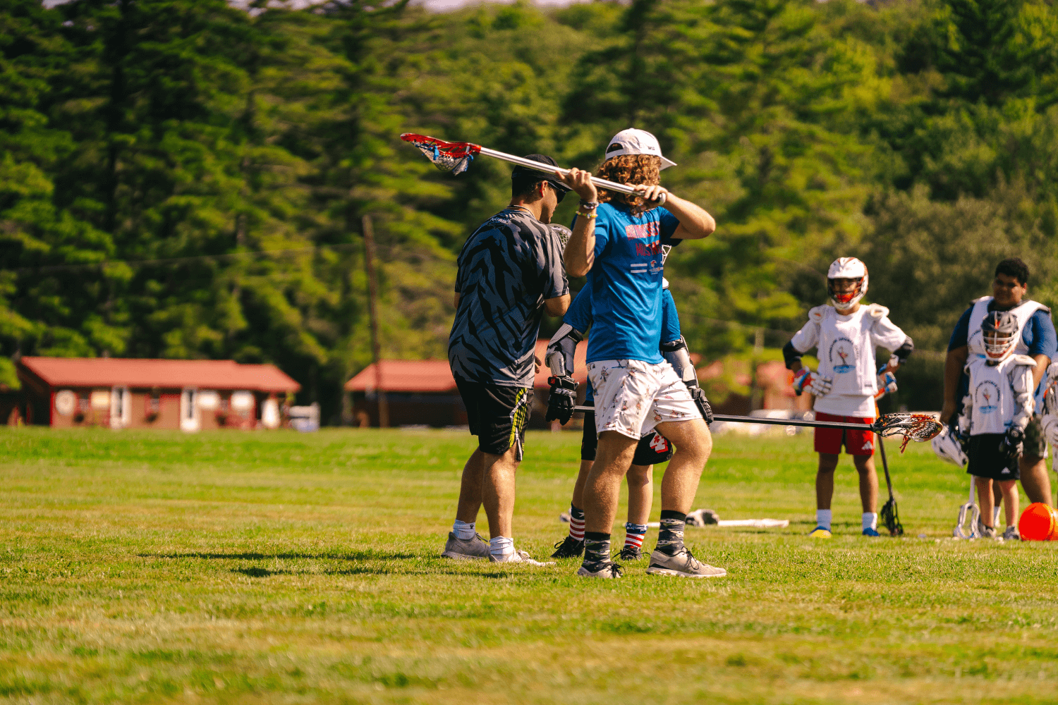 Overnight sports camp coaches giving instruction during lacrosse practice