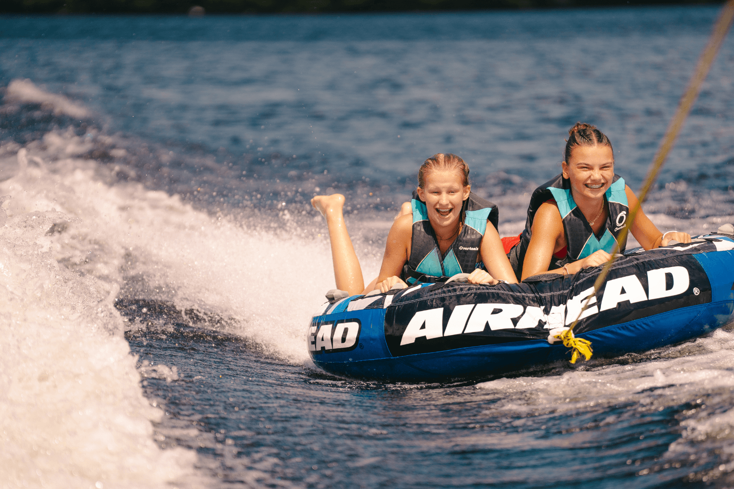 Girls smiling for a photo while tubing on the lake