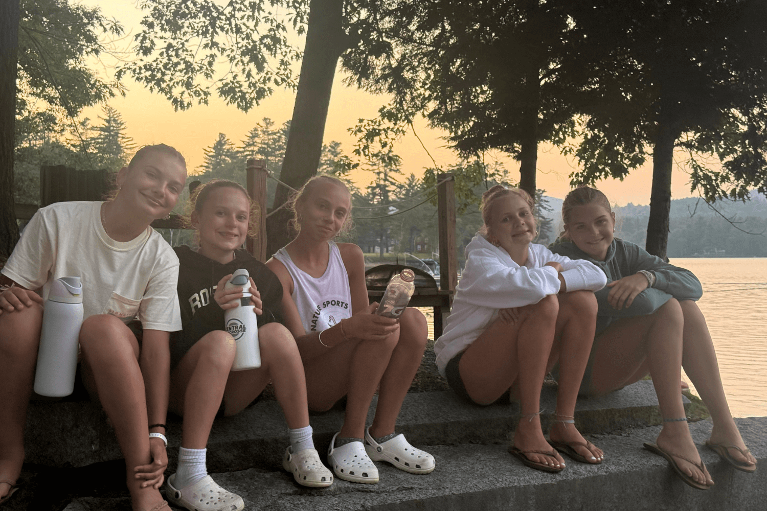 Girls at overnight sports camp relaxing by the water at sunset