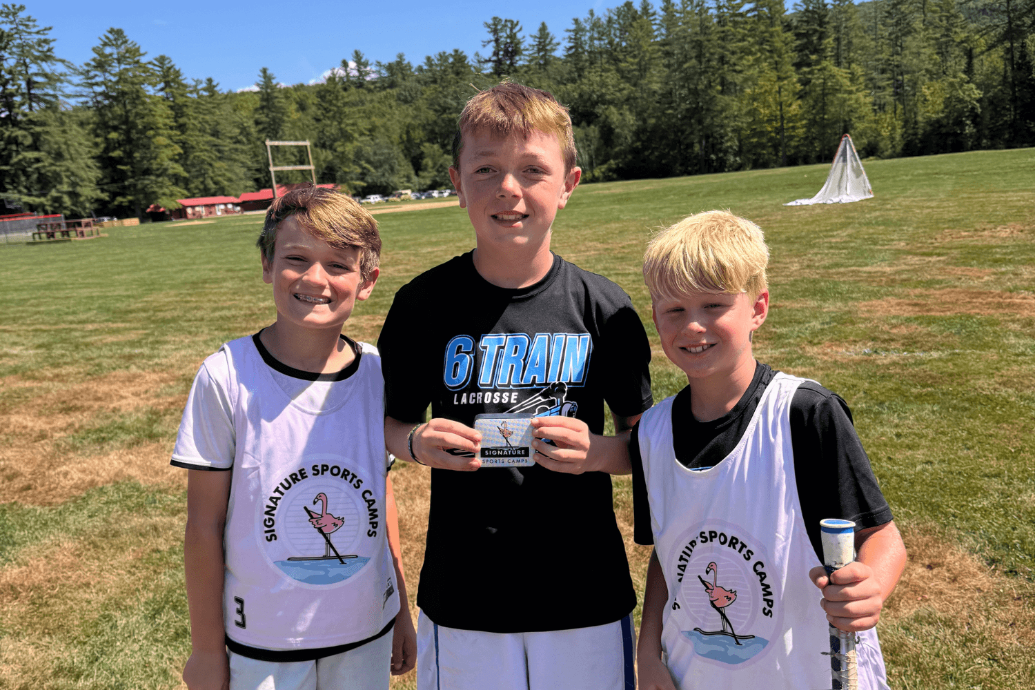 Boys smiling for a photo after lacrosse practice at camp