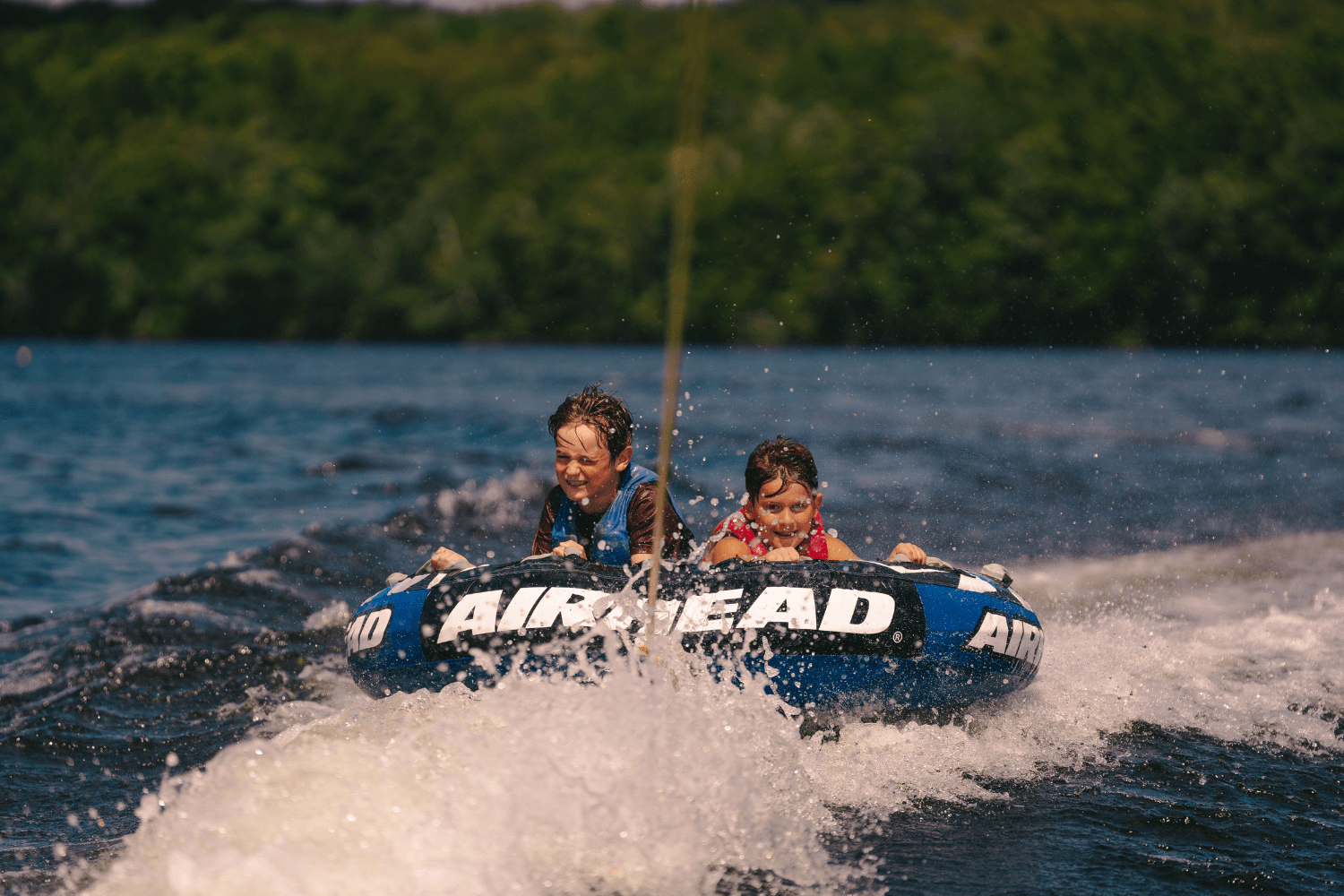 Two boys on a blue tube on the lake