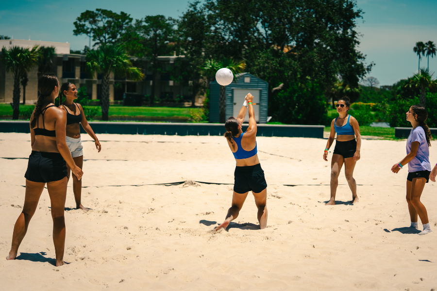 girls at overnight sports camp playing beach volleyball