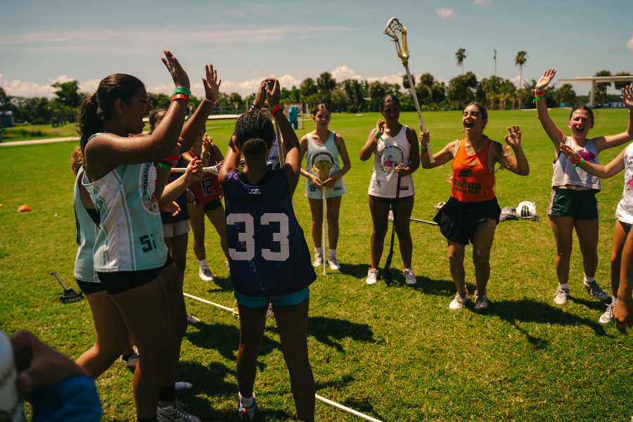 group of girls lacrosse players listening to their coach at camp