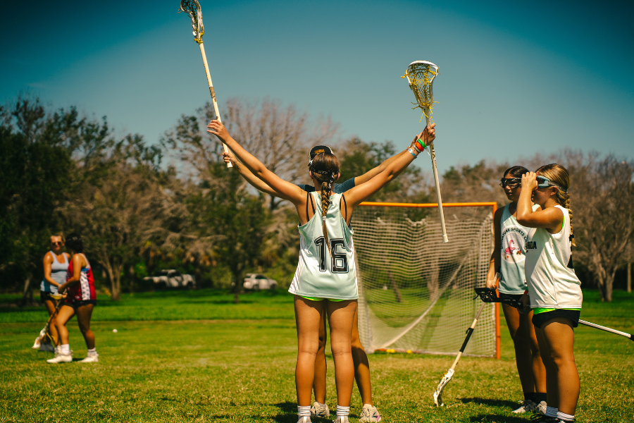 girls at lacrosse practice holding their sticks up