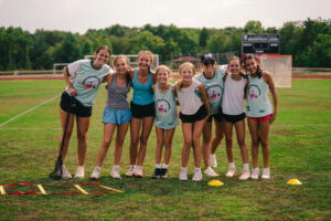 Signature sports camp coaches and athletes smile on the field during training