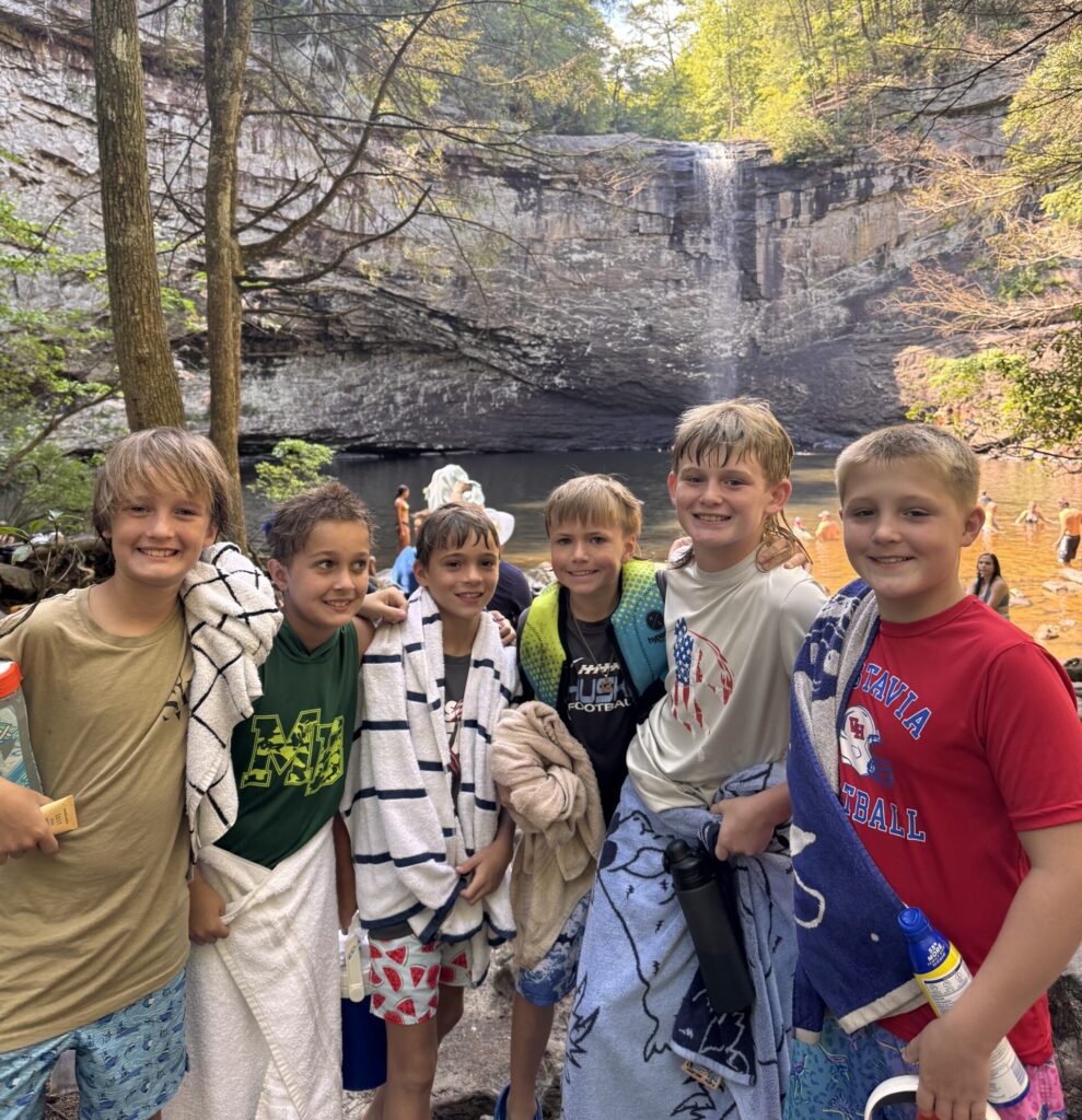 group picture of boy lacrosse players on a hike in front of waterfalls at overnight lacrosse camp
