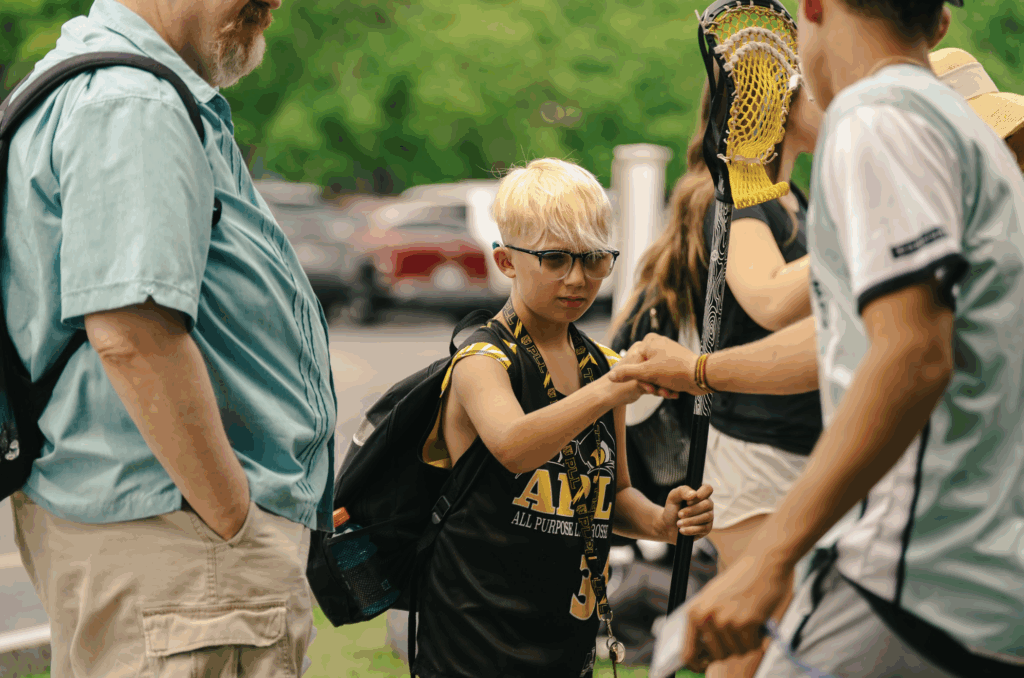 Boy lacrosse player fist bumping his coach during check-in at Signature Sports Camps