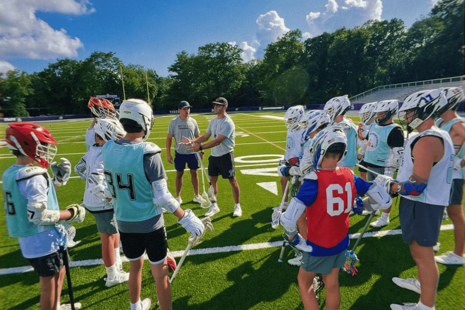 Boys on the lacrosse field listening to coaches