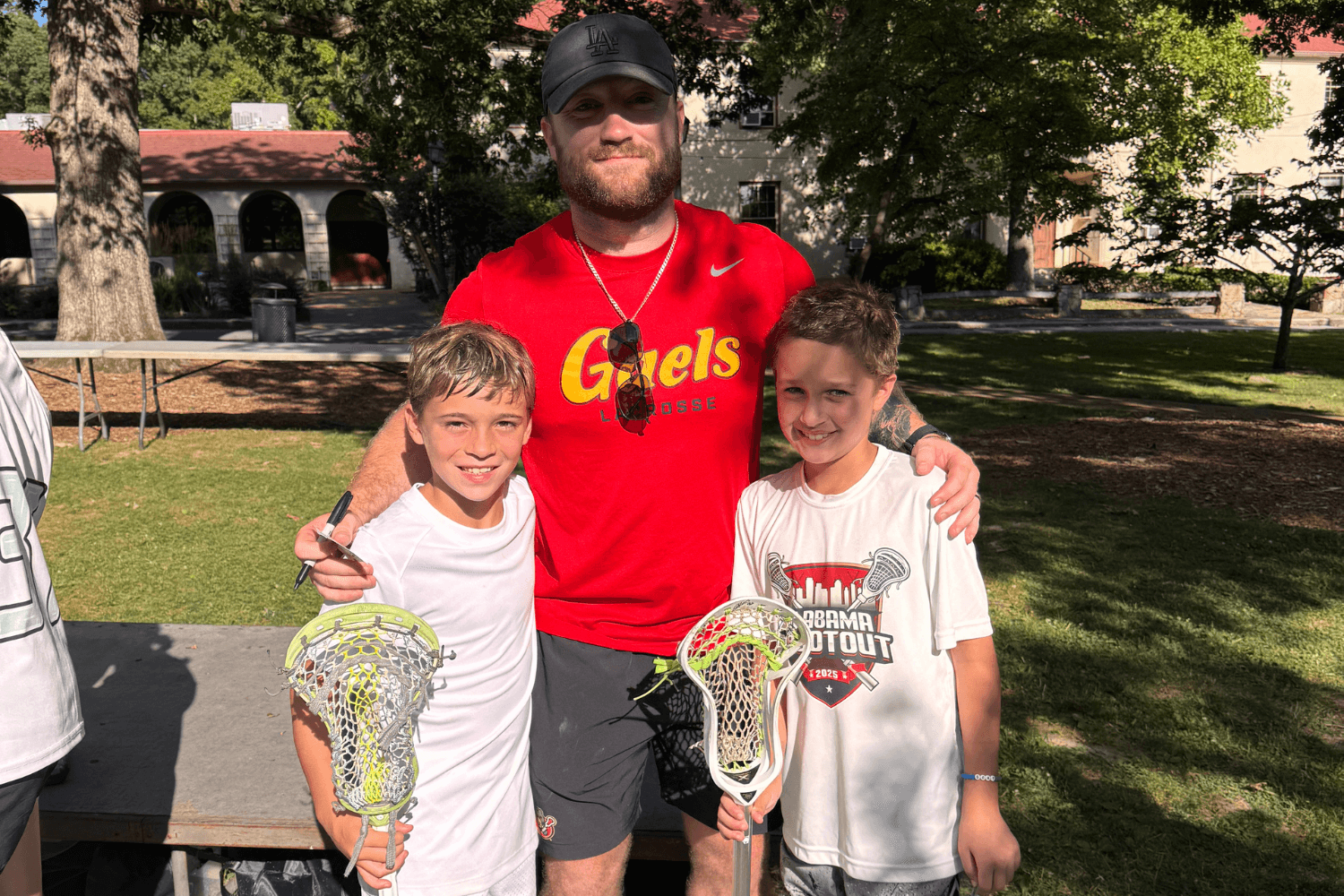 Boys smile for a photo with a lacrosse pro visiting overnight sports camp
