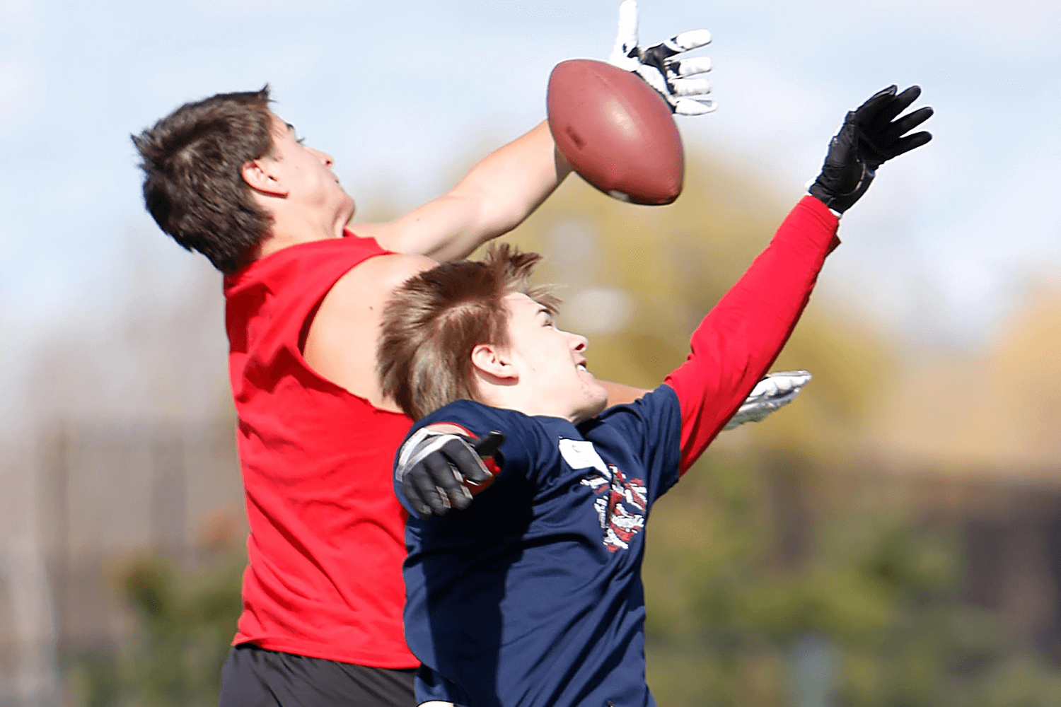 Two boys jumping for a football at sports camp