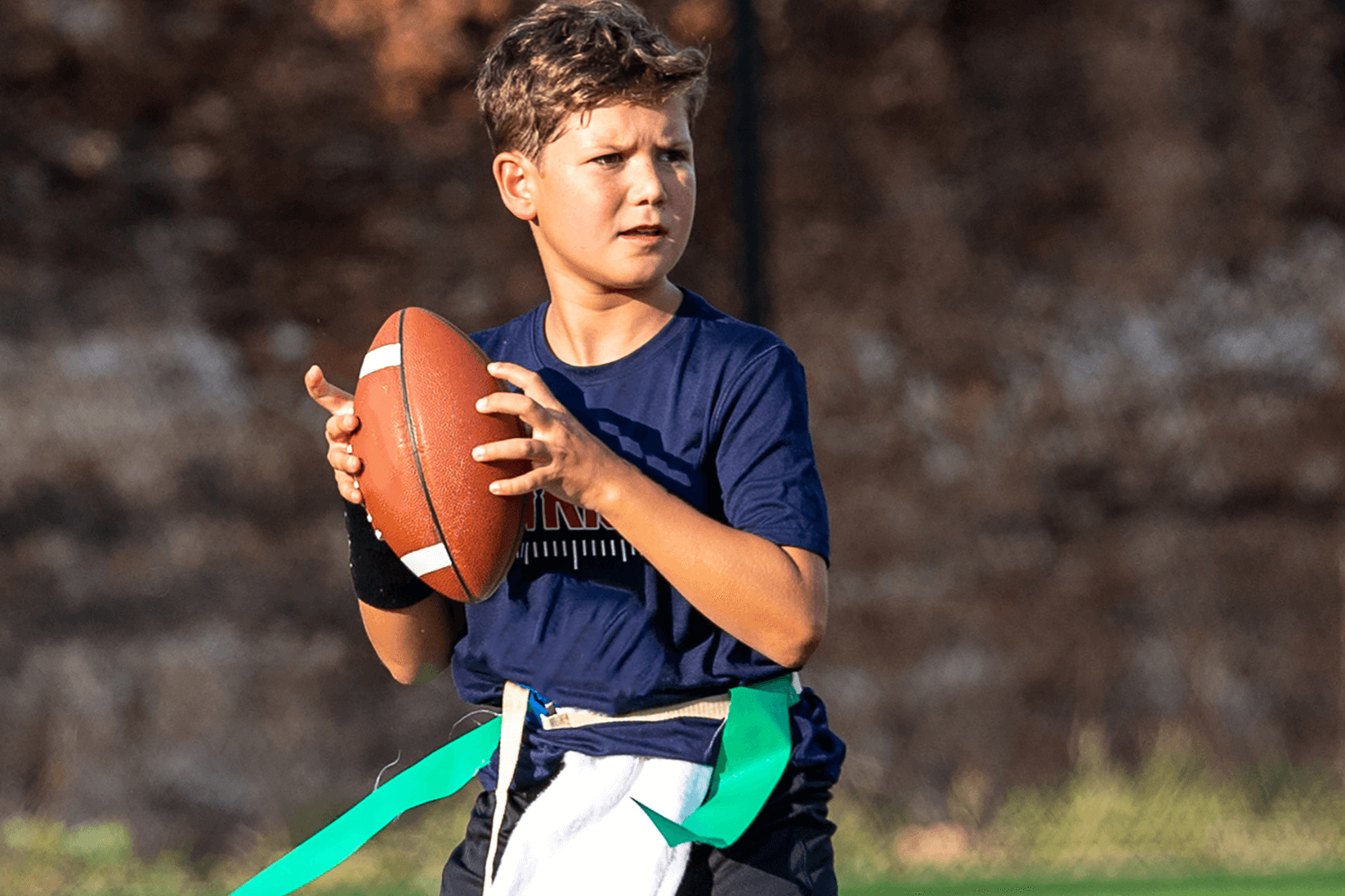 Boy playing quarterback during flag football at sports camp